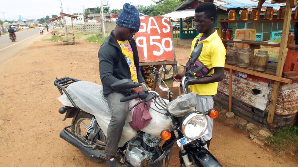 A man sells black market fuel to a motorbike rider on a road side in Paynesville, outside Monrovia, Liberia - Thursday 6 June 2022