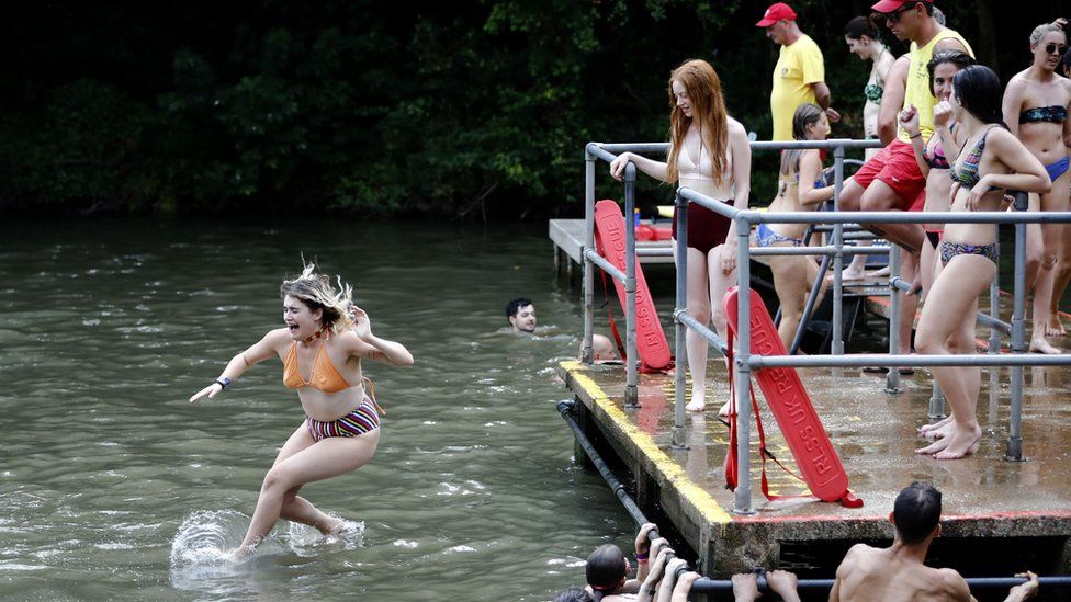 A girl jumps into the pond on Hampstead Heath