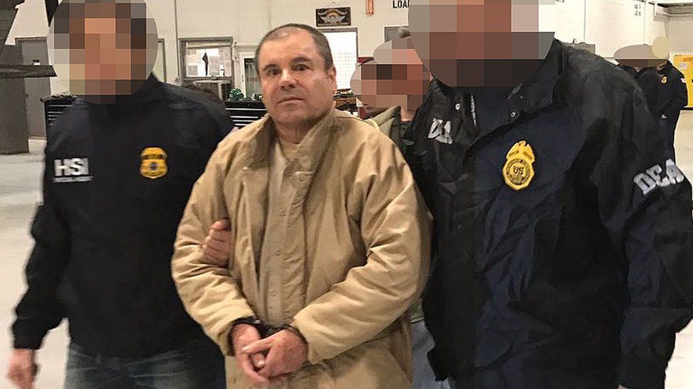 This handout picture released by the Mexican interior ministry shows Joaquín "El Chapo" Guzmán (centre) escorted by Mexican police officers before his extradition to the US. Photo: January 2017