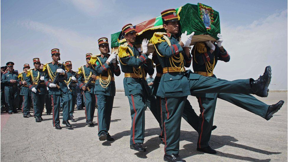 An Afghan honour guard carries the coffin of a policemen