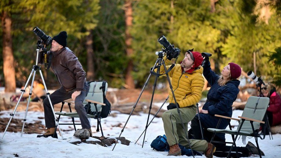 Photographers ready their tripods and cameras to capture the orange glow from water flowing off Horsetail Fall
