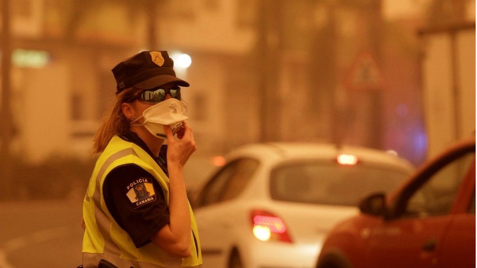 A female police officer holds her mask in place as she directs traffic on Tenerife
