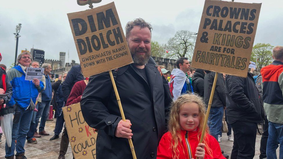 A man and his daughter holding placards