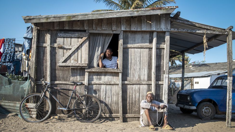 Мужчина сидит возле своего дома и читает на четках в Форт-Дофине, Мадагаскар