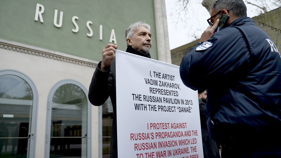Russian artist Vadim Zakharov holds up a placard distancing himself from his own country's invasion of Ukraine