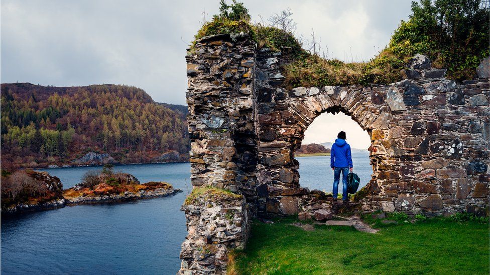 Female tourist at the ruins of Strome Castle on the shores of Loch Carron