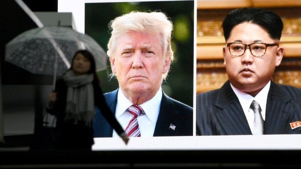 Woman in Tokyo walks past TV screen showing Donald Trump and Kim Jong-un