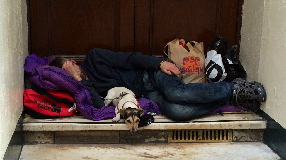 Homeless man sleeping in doorway with dog