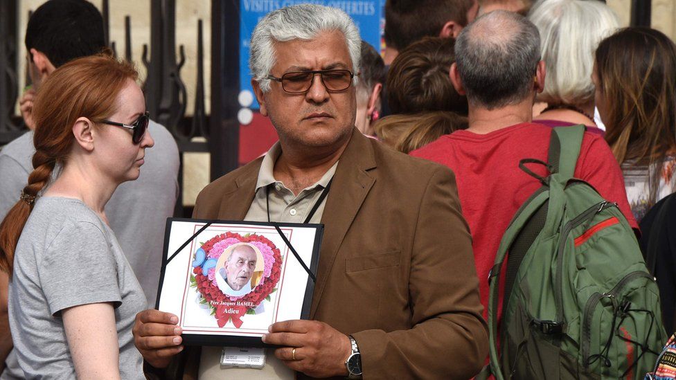 President of the Friends of Coptic association Gamil Gorgy holds a portrait of the priest Jacques Hamel reading "Farewell", outside Notre Dame Cathedral in Paris - 27 July