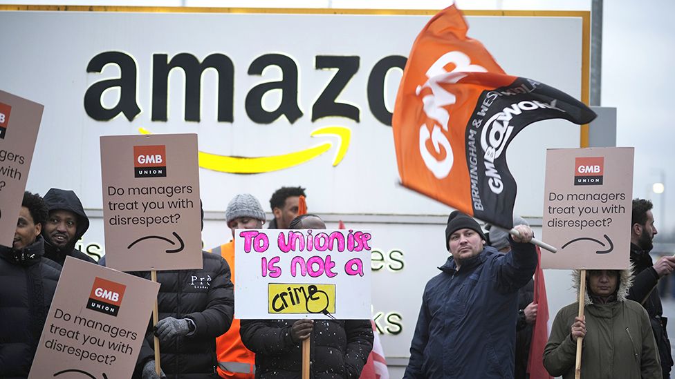 Amazon workers hold GMB union placards on the picket line as they hold a strike outside the Amazon fulfilment centre on January 25, 2023 in Coventry, England