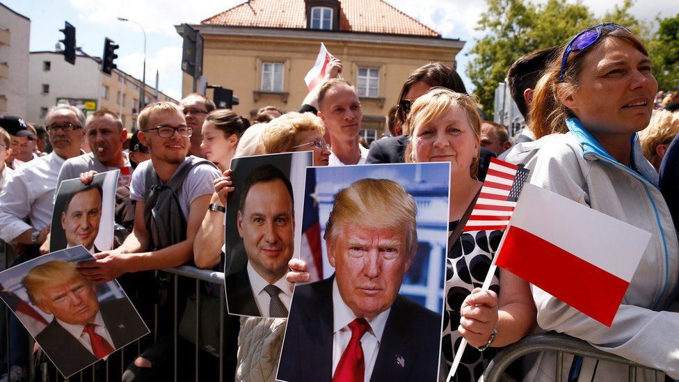 People holding portraits of US President Donald Trump and Polish President Andrzej Duda wait at Krasinski Square in Warsaw, 6 July