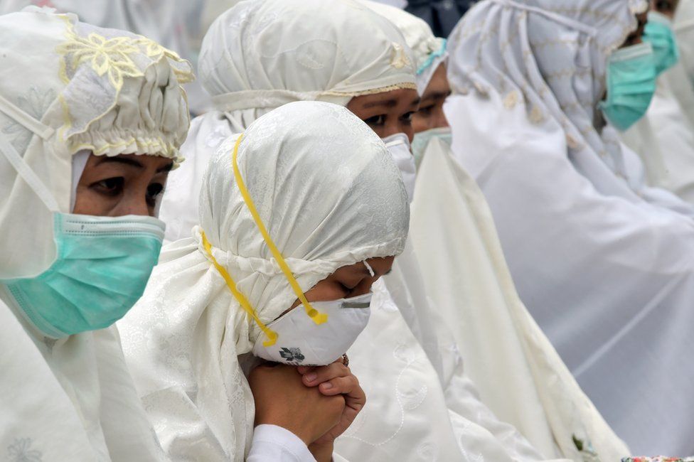Indonesian women wearing masks pray in Pekanbaru on 15 September 2015.