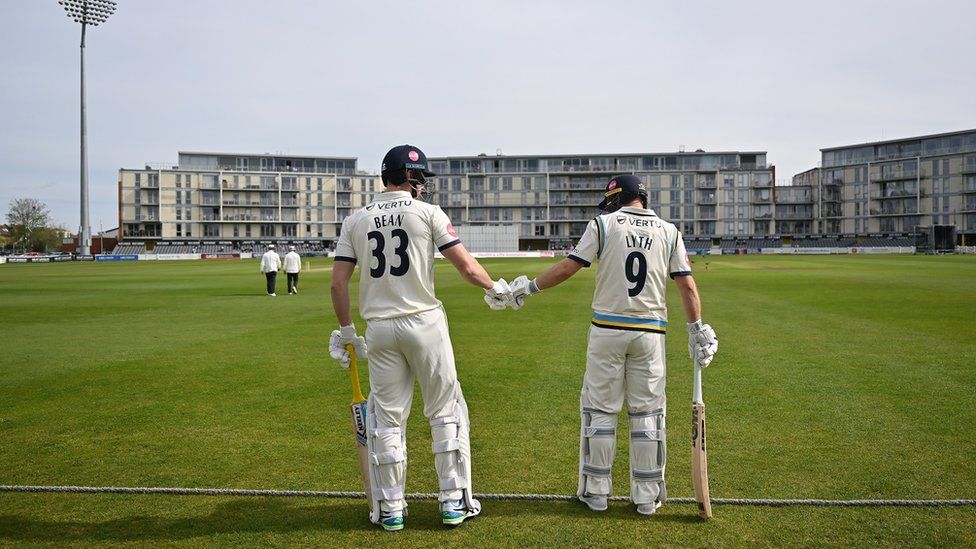 Two batsmen touch gloves as they stand on the boundary rope ahead of Gloucestershire v Yorkshire in Bristol