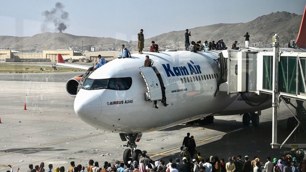 People sit on top of a plane at Kabul airport