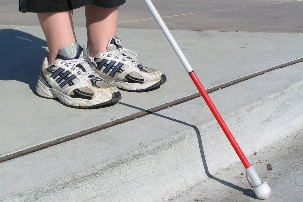 White cane over a road kerb
