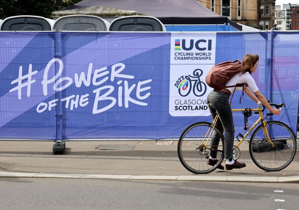 A woman cycles past signage in the city centre of Glasgow related to the UCI Cycling World Championships 2023 in Glasgow