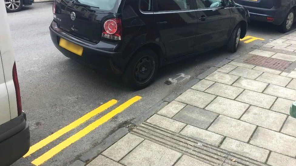 Double yellow lines painted around a black car
