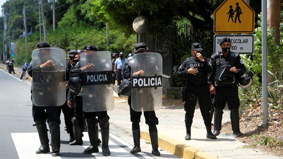 Полицейские Никарагуа стоят в строю, блокируя журналистов, работающих возле дома лидера оппозиции Кристианы Чаморро