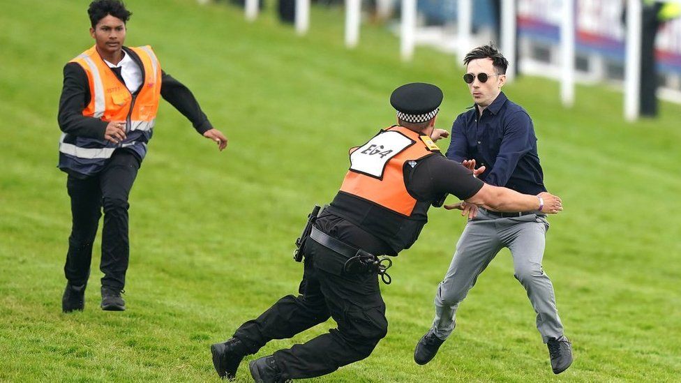 A protester is tackled by police and stewards during the Derby at Epsom Downs Racecourse, Epsom