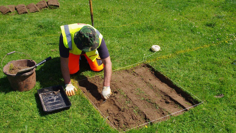 A man digging a small square in turf