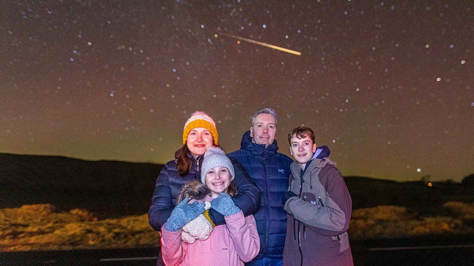 The family pose with shooting star in background