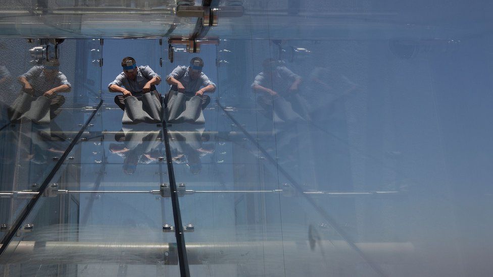 A man rides down a glass slide in Los Angeles