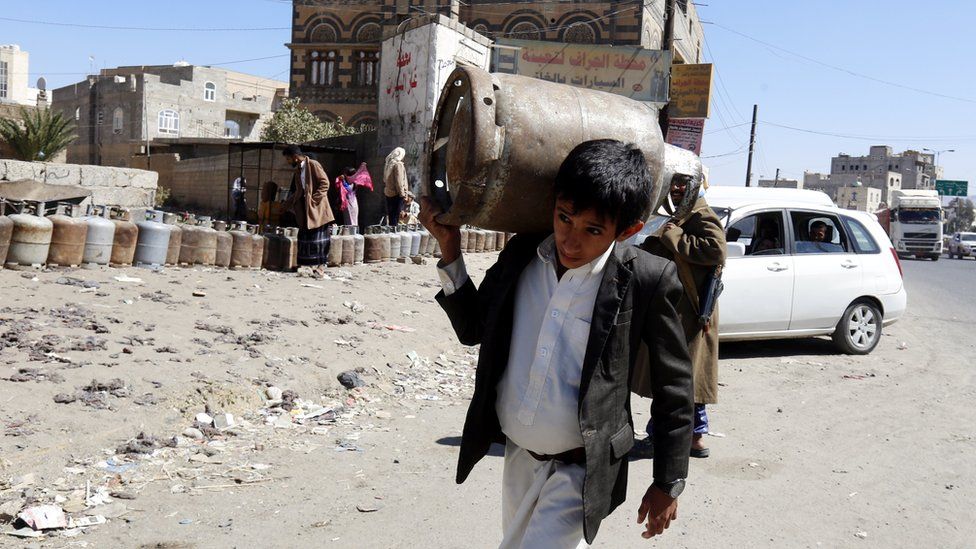 A Yemeni boy carries an empty gas cylinder as others wait for gas supplies in Sanaa, Yemen (7 November 2017)