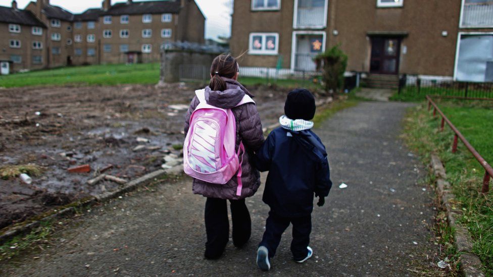 Two children walking to block of flats