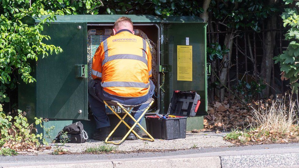 Engineer working in a green box with communications cables