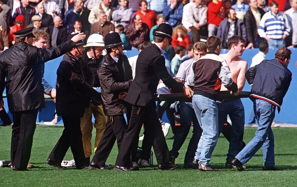 Police and fans carry away injured from the scene at Hillsborough