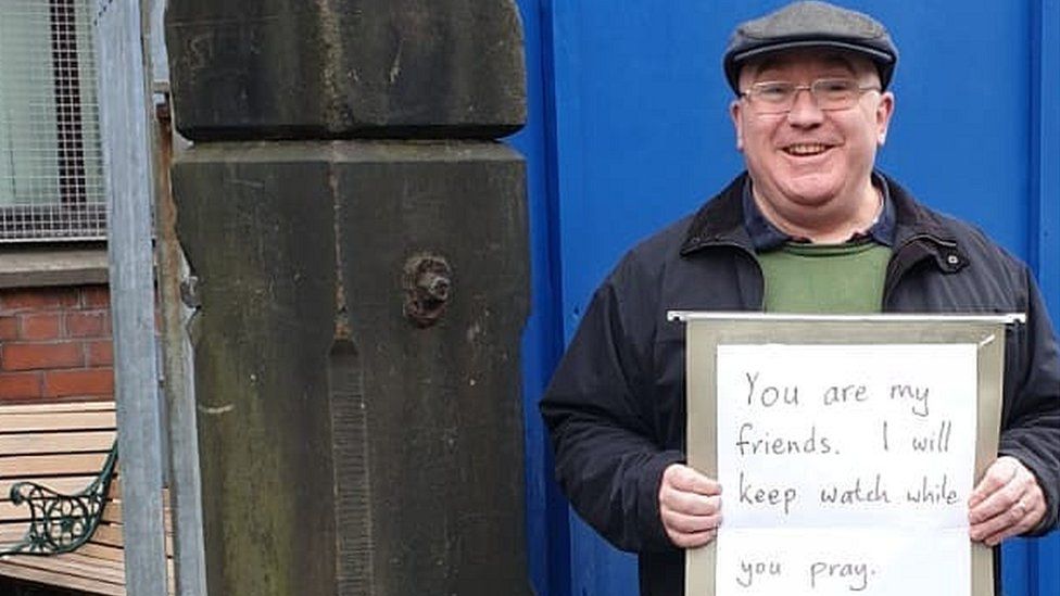 Andrew Graystone holding placard saying: "You are my friends. I will keep watch while you pray."