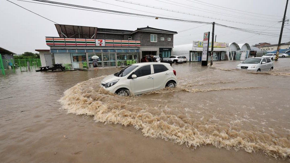 A vehicle makes its way along a waterlogged road following flooding caused by heavy rain in Cheongju, South Korea