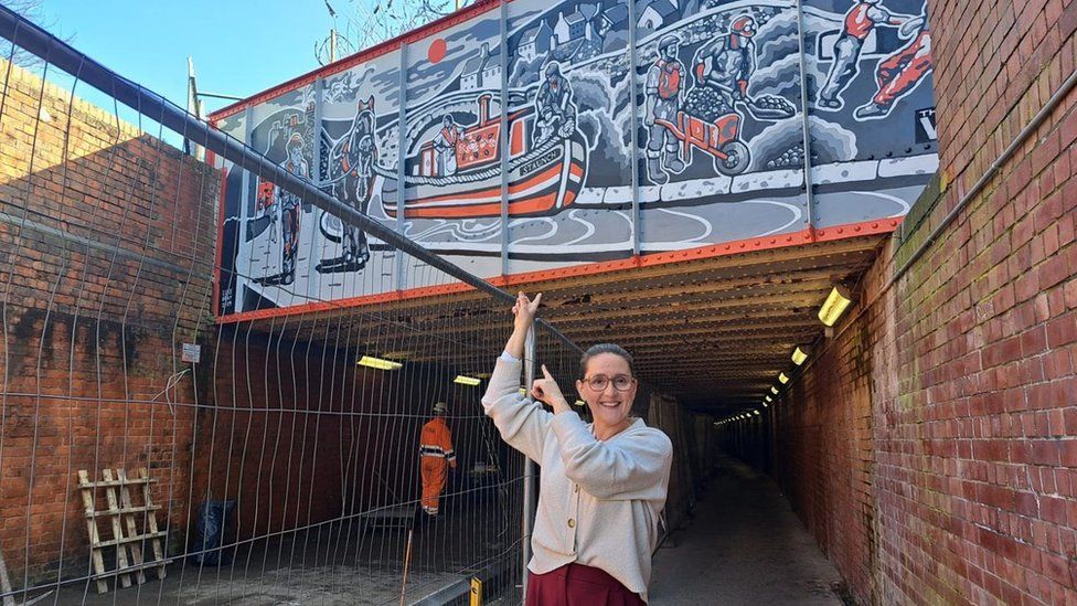 Marina Strinkovsky pointing to the mural in Swindon