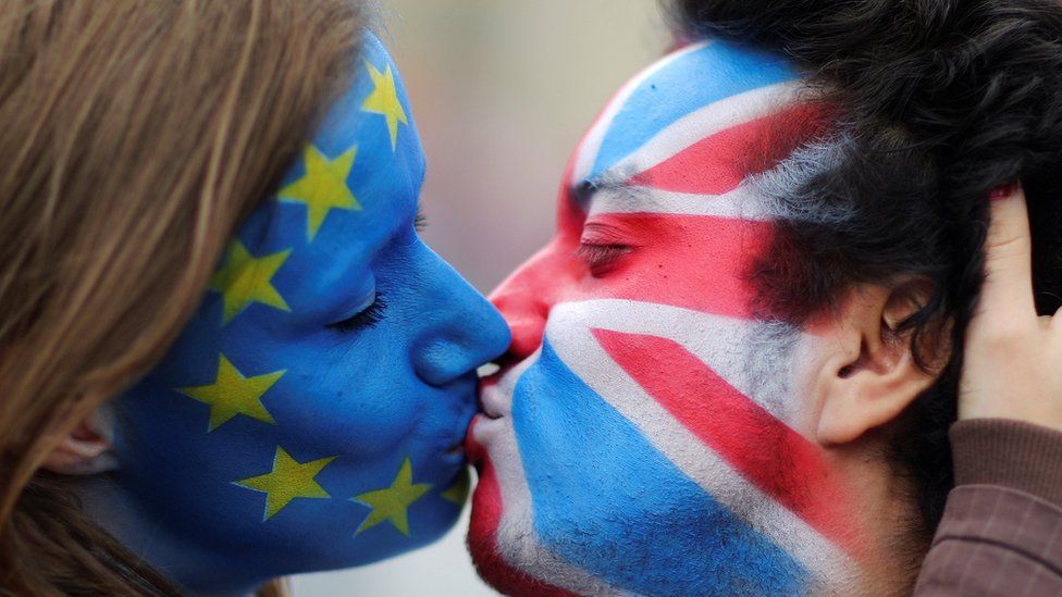 Two activists with the EU flag and Union Jack painted on their faces kiss each other in front of Brandenburg Gate to protest against the British exit from the European Union, in Berlin, Germany (June 19, 2016)