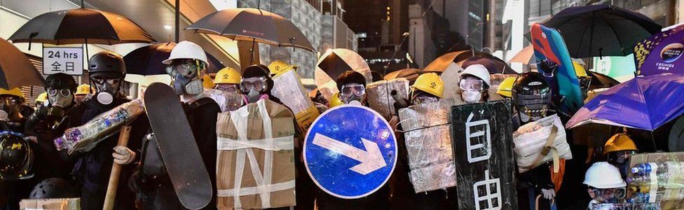 Protesters stand together with makeshift shields