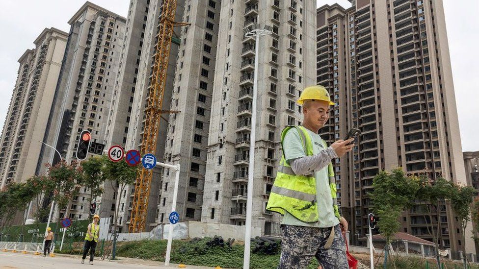 A worker walks past a housing complex under construction by Chinese property developer Evergrande in Wuhan, China on 28 September 2023.