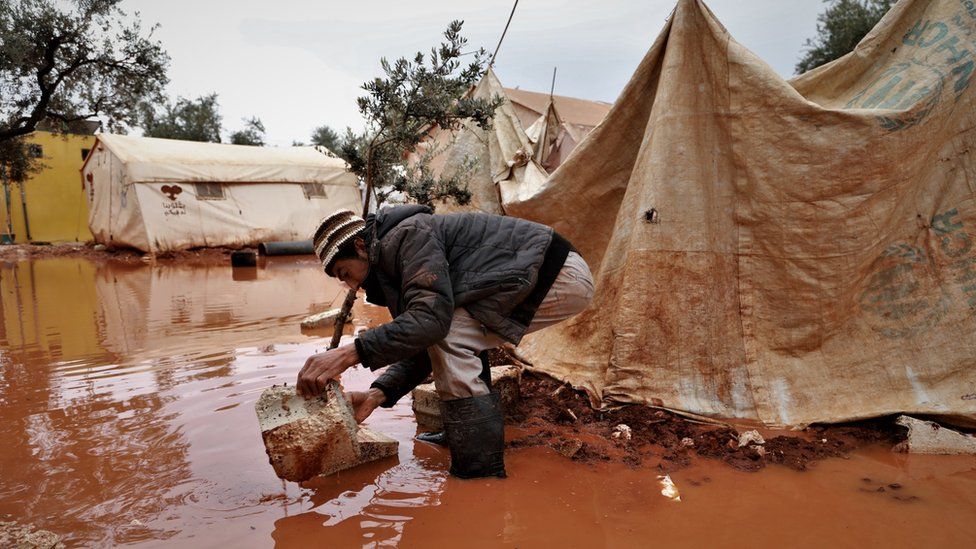 A man stands outside a flooded tent in Idlib province, Syria