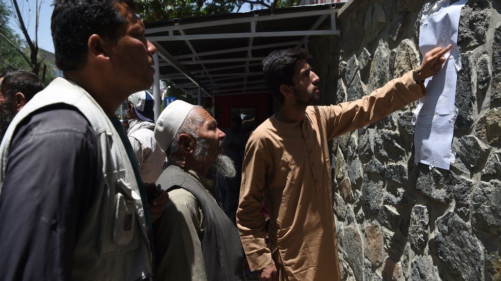 Men check a list of casualties after a car bombing in Kabul, 1 July
