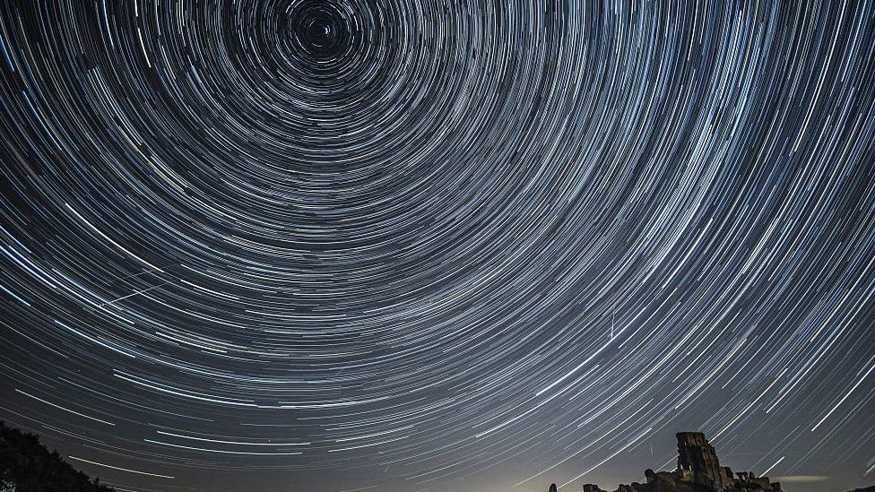 A long exposure shot of a meteor shower has produced streaks of white lines in a circle in the night sky