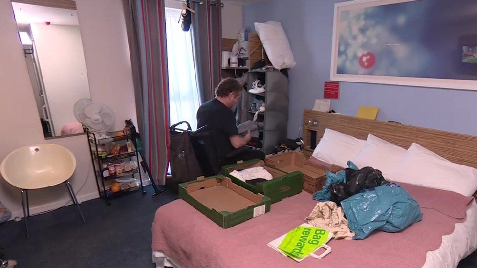Piotr Rembikowski packing up his hotel room to move again