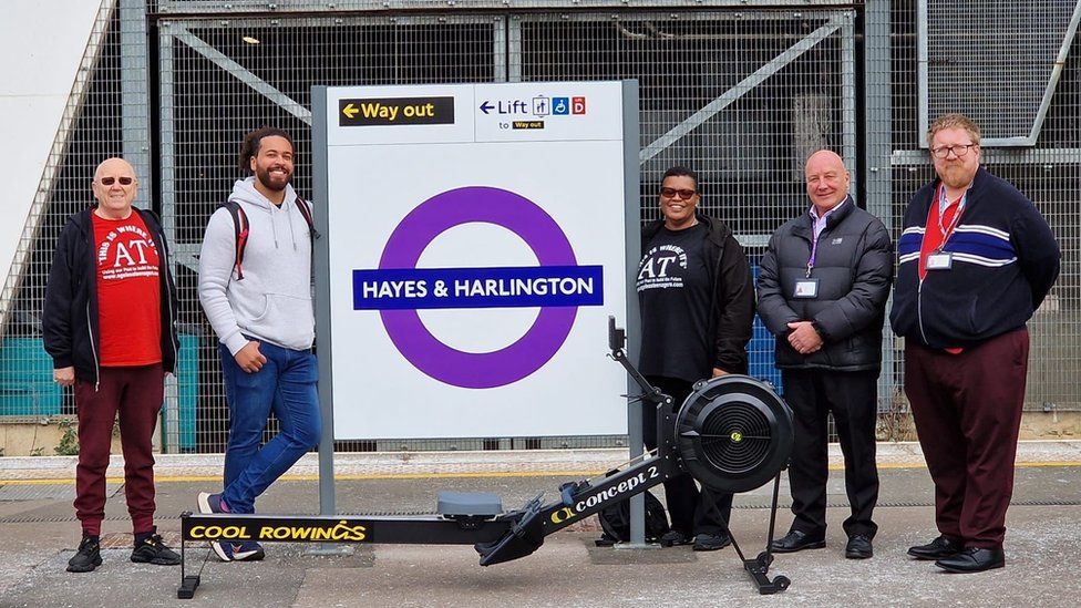Participants smile at Hayes and Harlington station with a rowing machine
