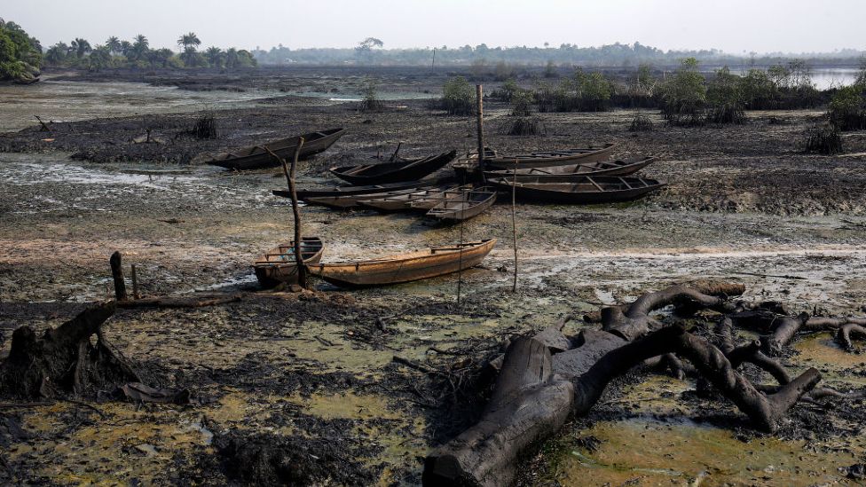 Abandoned fishing boats sit on the ground as crude oil pollution covers the shoreline of an estuary in the Niger Delta region, Nigeria