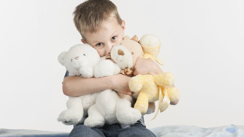 Young boy squeezing cuddly toys