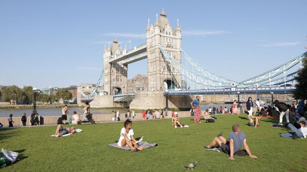 File image of people sunbathing with Tower Bridge in the distance
