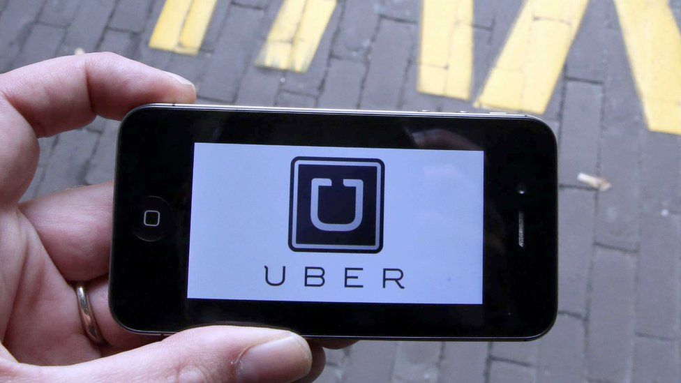 An Uber logo appears on a smartphone