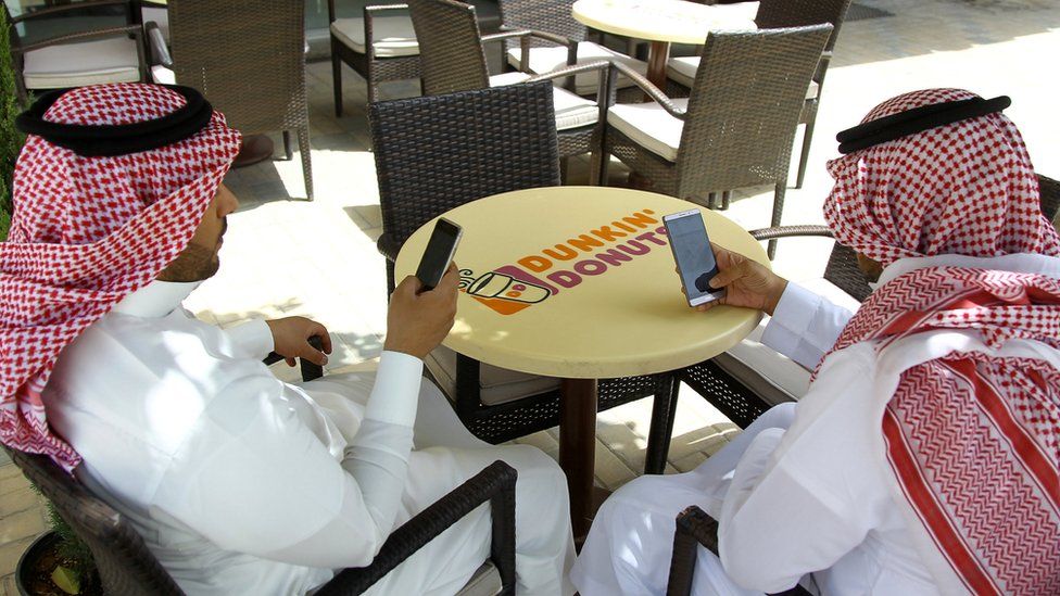 Saudi men explore social media on their mobile phones in a cafe in Riyadh