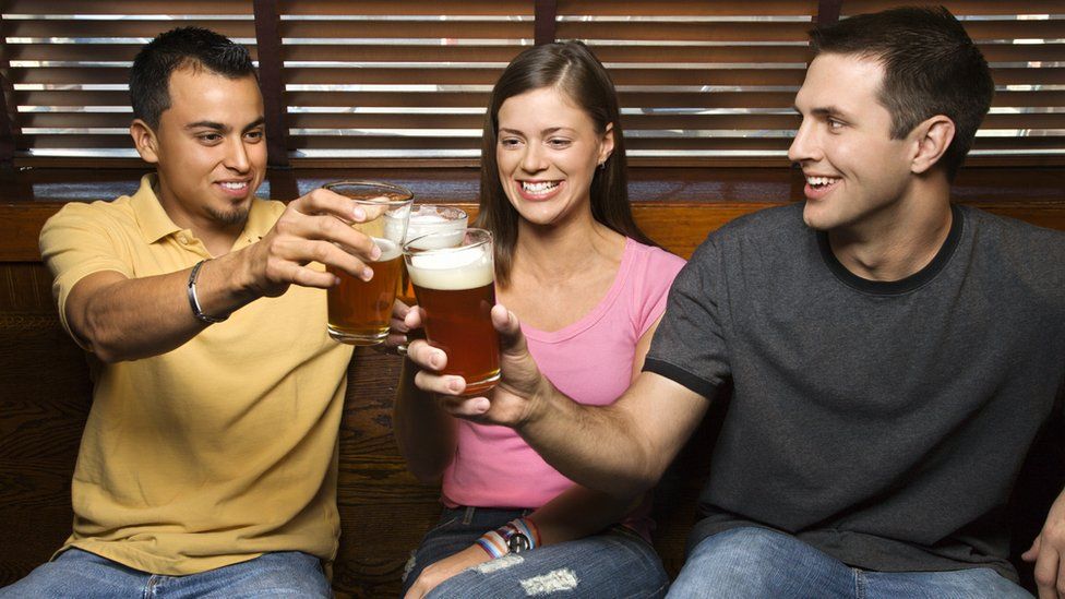 Two men and a woman drinking beer