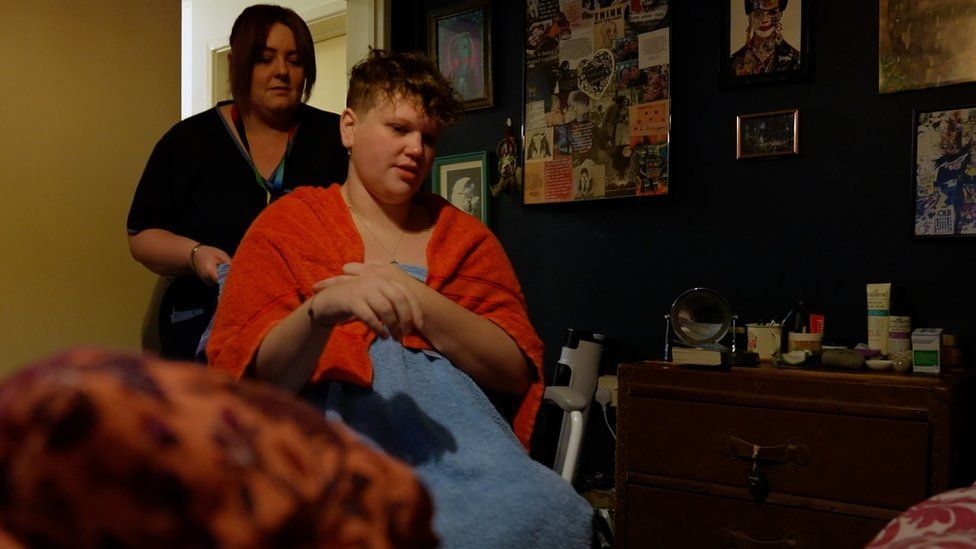 Georgie in her bedroom getting help from a carer