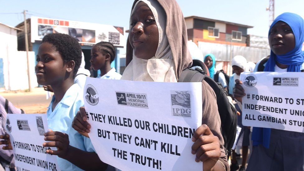 Demonstrators hold placards reading "They killed our children but they can't kill the truth" during a march in rememberance of victims of The Gambia's former regime, in Serekunda - April 2017