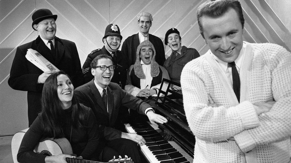 Corbett was spotted by David Frost, who recruited him for his satirical sketch show The Frost Report in 1966, where he worked alongside (back row l-r) Nicholas Smith, Ronnie Barker, John Cleese , Nicky Henson, (front row, l-r )Julie Felix,, Tom Lehhrer, Ronnie Corbett and David Frost